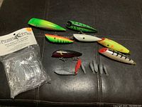 Fishing lures, weights, and clear plastic lure bodies on dark surface.