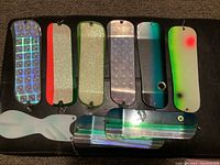 10 Pro-Trull fishing lures displayed in various colors and reflective metallic surfaces on a black background.