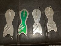 Four metal salmon fishing flashers with silver, green, and blue finishes, showing front side of the flashers.