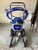 Front view of sprayer showing Graco Magnum X7 TrueAirless label, coiled hose on handle