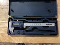 Electronic caliper inside its black carrying case showing the digital display and stainless steel measuring scale.