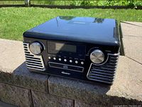 Front view of black Memories radio, CD, and turntable unit showing central screen, control knobs, and speaker grills.