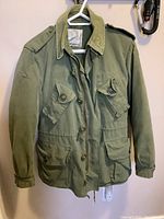 Front view of green military army combat jacket showing pockets, buttons, collar, and epaulets.