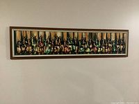 Full view of horizontal oil painting with multiple bottles in abstract style, framed in silver.