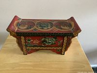 Image of the Oriental wooden jewelry box showing the top and front, highlighting the hand-painted floral and bird designs and pagoda-style roof lid.