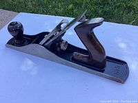 Side angle view showing the full Stanley Bailey #5 corrugated hand plane with wooden handles and metal body on a white background.