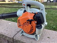 Side view showing orange engine cover, white housing, fuel tank and black muffler