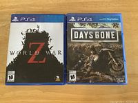 Photo shows two PS4 game cases: World War Z and Days Gone, both front cover visible on wooden background.