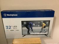 Front of the box displaying Westinghouse 32 inch LED HDTV with image showing ice hockey game.