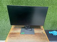 Front view of the Dell 27" monitor showing screen and adjustable stand with attached cables.
