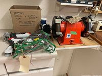 Photo showing Creusen bench grinder on wooden platform with tools in front including a Black & Decker saw and drill