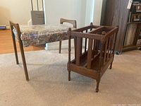Wooden bench with floral cushioned seat and wooden magazine rack side by side on carpeted floor showing overall size and style.