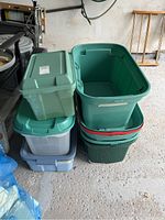 Stacked storage bins of varying sizes and colors including green and gray, with lids.