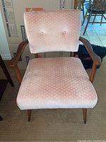 Front view of wood frame chair showing light pink upholstery with small polka dots and button-tufted backrest.