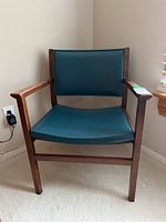 Front view of the wood framed chair with teal vinyl seat and backrest showing the overall condition.