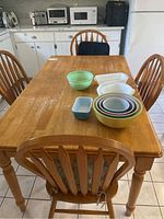 Four wooden dining chairs around a table with cushions visible on seats.