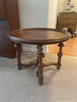 Side and angled view of the round wooden table showing turned legs and stretcher support.