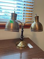 Full view of the metal desk lamp showing both adjustable metal shades with perforated edges, brass base and dark metal stem.