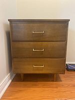 Front view of the wooden chest dresser showing three drawers and metal handles.