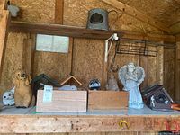 Shelf with all figurines, bird feeders, watering can, and wood boxes on display in the shed.
