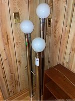Full view of chrome three-column floor lamp with three white opal glass globes