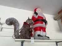 Plastic Santa and lighted squirrel on a shelf, both intended for outdoor Christmas decoration.