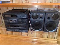 Front view of Panasonic stereo system with two deck cassette/CD player unit and two Panasonic S-XBS speakers with connected wiring
