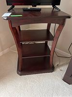 Front view of wooden shelf showing three shelves and curved supports