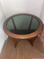 Full top view of the round wood table with smoked glass inset showing the wood grain frame and reflective glass surface.