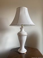 Full view of one matching ceramic table lamp with white fabric shade and gold trim.
