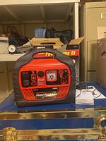 Front and top view of Wagan Tech Power Dome EX 400 watt generator on blue surface with shelving in background.