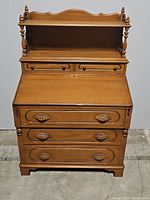 Front view of antique burl maple secretary desk with small hutch, 5 drawers, and two shelves.