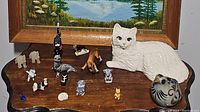 Wide view showing the assortment of 16 animal figurines on wooden surface with a painting in the background