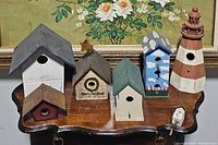 Overview of all 7 birdhouses showing varied designs, colors, including lighthouse and Merry Christmas themed birdhouses.