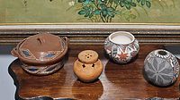 Four decorative clay pots arranged on a table with painting background, showing size, shape and detail variations.