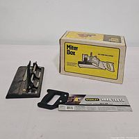 Stanley Hard Tooth Back Saw displayed alongside a metal miter box and its original packaging box showing 'Miter Box' and 'No Saw Included' text.