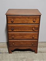 Front view of vintage tall boy dresser with all drawers closed, showing wood finish, four drawers, and wooden knob handles.
