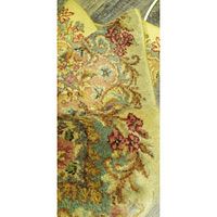 Close-up of the ornate floral pattern in beige, red, blue and green with soft texture on the area rug.