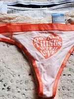Set of four women's XL thongs laid on a textured light surface, showcasing various styles and brand tags, including Calvin Klein and INC tags.