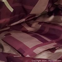 Interior of handbag showing fabric lining with light and dark brown geometric pattern and inner zippered pocket.