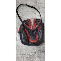 Full front view of vintage purse showing black leather with red textured leather panel details and shoulder strap.