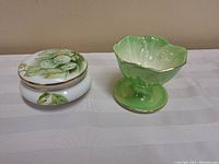 Two antique china bowls: Rosenthal lidded bowl with painted floral design and Maling green pedestal bowl, displayed on cloth.