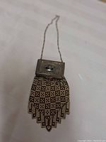 Overall front view of the antique 1920s metal link purse with compact clasp showing black silhouette decoration on the compact.