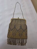 Front view of antique metal mesh purse showing metal frame, chain, detailed mesh work, and fringe with minor damage.