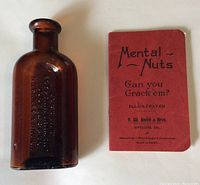 Brown glass medicine bottle and red puzzle booklet titled 'Mental Nuts Can you Crack 'em?' from F.W. Smith & Bros. Jewellers.