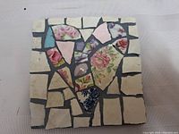 Top view of the 6 x 6 inch mosaic featuring floral crockery pieces arranged in a heart shape with contrasting grout.