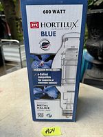 Photo of the EYE Hortilux 600 watt Blue metal halide grow light bulb box with product details and branding visible.