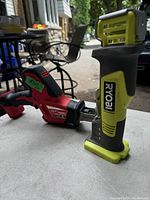 Photo showing Milwaukee Hackzall and Ryobi saw side by side on a table outdoors.