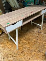 Full view of the desk showing oak finish top with paint stains, white metal base, and two drawers on the front left side