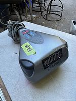 Side/top angled view of percussion massager showing overall shape, power cord, and brand sticker